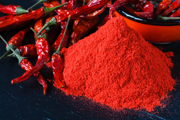 Composition with bowl of chili powder on wooden table